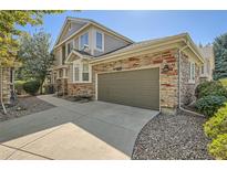 Exterior view of a tan two-story home, showcasing a two-car garage with a stone facade at 3546 Broadlands Ln # 102, Broomfield, CO 80023