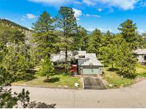 Charming single-Gathering home featuring an attached garage and basketball hoop surrounded by mature trees at 997 Dogwood Dr, Golden, CO 80401