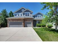 Beautiful two-story home with a stone facade and a three-car garage, set against a bright blue sky at 7329 Arco Iris Ln, Castle Pines, CO 80108