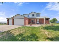 Charming two-story home with a three car garage, brick facade, and a well-manicured lawn at 5602 County Road 15, Fort Lupton, CO 80621