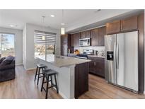 Modern kitchen boasts stainless steel appliances, granite countertops, and wood cabinets at 5110 E 64Th Ave, Commerce City, CO 80022