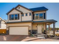 Charming two-story home with tan siding, dark shutters and a covered porch, blending modern and traditional design elements at 10512 Truckee St, Commerce City, CO 80022