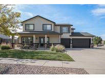 Two-story home featuring manicured lawn, a three car garage, and a charming stone facade at 504 Branding Iron Ct, Brighton, CO 80601
