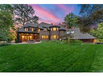 Expansive backyard featuring a large brick home, outdoor patio, and manicured lawn at dusk at 4600 E 3Rd Ave, Denver, CO 80220