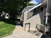 Tan siding on this 2-story condo with nearby sidewalk and mature landscaping at 12478 W Nevada Pl # 207, Lakewood, CO 80228