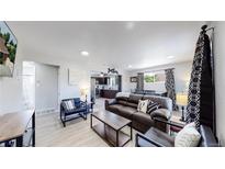 Open-concept living room showcases contemporary decor and transitions seamlessly into the kitchen and dining area at 7020 Avrum Dr, Denver, CO 80221