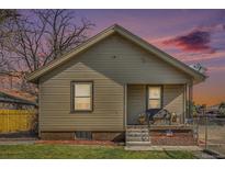 Charming single story home featuring vinyl siding, a cozy front porch and a well-kept front lawn at sunset at 6411 E 64Th Ave, Commerce City, CO 80022