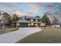 Beautiful two-story home with a long driveway and attached garage under a colorful dawn or dusk sky at 6764 Hillridge Pl, Parker, CO 80134