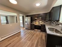 Modern kitchen featuring stainless steel appliances, dark cabinets, and a stylish backsplash at 8307 E 14Th Ave, Denver, CO 80220