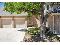 Charming brick townhome featuring a two-car garage, quaint front yard, and mature shade tree at 1470 S Quebec Way # 83, Denver, CO 80231