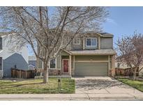 Two-story home with well-maintained lawn and two-car garage, featuring a red front door and stone accents at 9615 Lansing Cir, Commerce City, CO 80022