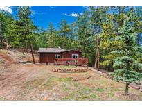 Cozy cabin with wood siding and a charming deck surrounded by lush greenery at 23778 Inca Rd, Indian Hills, CO 80454