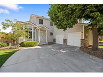 Charming two-story home featuring an attached two-car garage, well-kept lawn, and beautiful mature trees at 15157 E Nassau Ave, Aurora, CO 80014