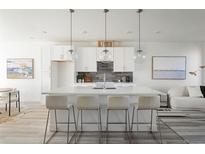 Bright, white kitchen featuring an island with bar seating and stylish pendant lighting at 8 Oneida Ct, Denver, CO 80230