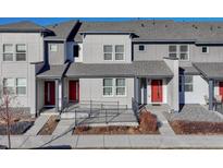 Modern townhome with gray siding, red door, and accessible ramp at 16023 E Warner Pl, Denver, CO 80239