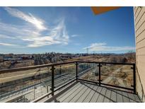 Balcony with clear glass railing and view of railroad tracks, walking path, and mountains beyond at 1208 N Quitman St # 402, Denver, CO 80204