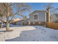 Gray exterior boasts brick accents and a spacious yard with a wooden fence at 16046 E Harvard Ave, Aurora, CO 80013