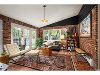 Relaxing sunroom featuring exposed brick, large windows, and cozy seating area with unique artistic touches at 4011 S Ivy Ln, Cherry Hills Village, CO 80111