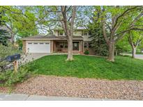 Charming two-story home with brick accents, mature trees, lush lawn, and a two car garage at 6222 S Ames Ct, Littleton, CO 80123