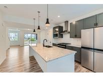 Modern kitchen boasts gray cabinets, stainless steel appliances, and a large island with pendant lighting at 1755 Peak Loop, Broomfield, CO 80023