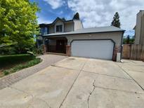 Two-story home featuring an attached garage, brick accents, and a large driveway at 3136 S Cathay Cir, Aurora, CO 80013