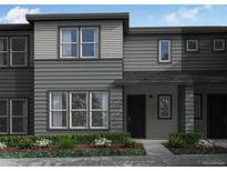 Two-story townhome with gray siding, black doors, large windows, and professionally landscaped front yard at 16787 W 94Th Way, Arvada, CO 80007