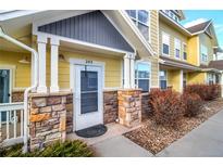 Welcoming entryway with charming stone accents and bright yellow siding, leading to a cozy home at 9335 Amison Cir # 203, Parker, CO 80134