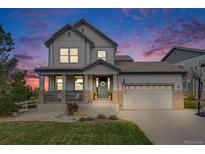 Beautiful two-story home with a welcoming front porch and well-maintained landscaping at dusk at 703 Tiger Lily Way, Highlands Ranch, CO 80126