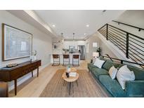 Open-concept living room with modern staircase, stylish furniture, and hardwood floors at 1473 N Locust St, Denver, CO 80220