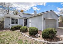 Charming home showcasing its light blue siding, well-manicured landscaping, and attached two-car garage at 17802 E Bates Ave, Aurora, CO 80013