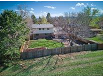 An aerial view of the home's spacious backyard, featuring a large lawn, mature trees, and a wooden fence at 9787 W Ohio Ave, Lakewood, CO 80226