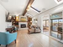 Bright living room with skylights, fireplace, and open access to the enclosed patio at 9787 W Ohio Ave, Lakewood, CO 80226