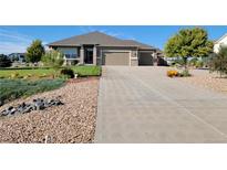 Beautiful single-story home with a well-maintained front yard, a long driveway and a two car garage at 16231 Rayburn St, Hudson, CO 80642