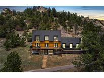 Modern exterior elevation of mountain home, featuring a large deck and steps to driveway at 6640 Kilimanjaro Dr, Evergreen, CO 80439