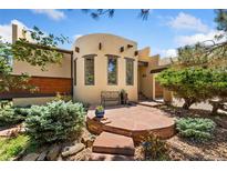 Inviting front entrance with a stone patio, bench, and charming Southwestern architectural details at 6457 Willow Broom Trl, Littleton, CO 80125