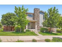 Charming two-story home featuring stone accents, a well-manicured lawn, and lush greenery at 15437 W 95Th Ave, Arvada, CO 80007