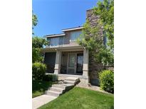 Charming two-story home featuring stone accents, a welcoming front porch, and beautifully landscaped yard at 15437 W 95Th Ave, Arvada, CO 80007