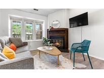 Bright living room with fireplace, large windows, stylish furniture, and wood-look flooring, perfect for relaxing at 3050 W 107Th Pl # E, Westminster, CO 80031