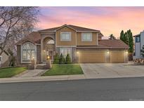 Inviting two-story home featuring a three-car garage, manicured lawn, brick accents, and a warm, painted facade at 553 Ouray Ave, Broomfield, CO 80020