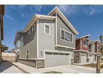 New construction home featuring a two-car garage with stone accents and gray horizontal siding at 4327 E 98Th Pl, Thornton, CO 80229