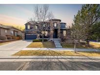 Beautiful two-story home with a well-manicured lawn, stone accents and a three car garage in a suburban neighborhood at 16658 E 106Th Dr, Commerce City, CO 80022