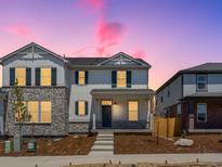 Charming two-story home with stone accents, black shutters, and inviting front porch at dusk at 22495 E 7Th Pl, Aurora, CO 80018