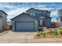 Charming two-story home with blue siding, a two-car garage, and landscaped front yard at 965 Arapahoe Cir, Louisville, CO 80027