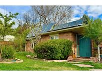 Brick home featuring solar panels, a blue front door, and beautiful landscaping at 805 Union Ave, Boulder, CO 80304
