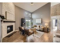 Inviting living room boasts a brick fireplace, vaulted ceilings, and a sliding door to the outdoor balcony at 9481 E Mansfield Ave # 301, Aurora, CO 80014