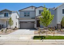 Charming two-story home with gray siding, landscaped front yard, and two car garage at 2162 Flower Blossom Ave, Brighton, CO 80601