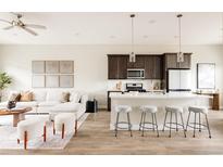 Open-concept living room and kitchen featuring a stylish island, modern furniture, and hardwood floors at 6307 Dayton Ct, Denver, CO 80238
