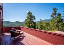 Inviting red wood deck offers stunning mountain and tree line views with seating for relaxing at 7350 Timber Trail Rd, Evergreen, CO 80439