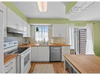 Well-lit kitchen featuring modern white cabinets, stainless steel appliances, and butcher block countertops at 9278 W Ontario Dr, Littleton, CO 80128