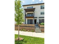Modern two-story townhome featuring a balcony, gray garage door, and well-manicured landscaping at 2108 Alcott Way, Broomfield, CO 80023